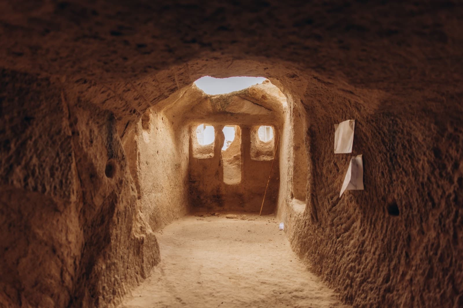 A carved cave passage opening to arched windows of light